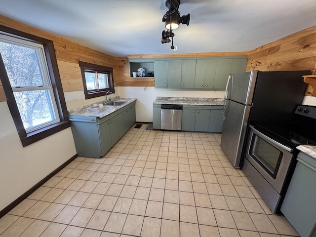 kitchen with sink, wooden walls, appliances with stainless steel finishes, and light tile patterned flooring