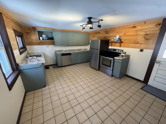 kitchen with wood walls, sink, stainless steel appliances, and light tile patterned flooring