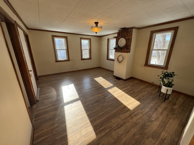 spare room with dark hardwood / wood-style floors, ornamental molding, and a healthy amount of sunlight