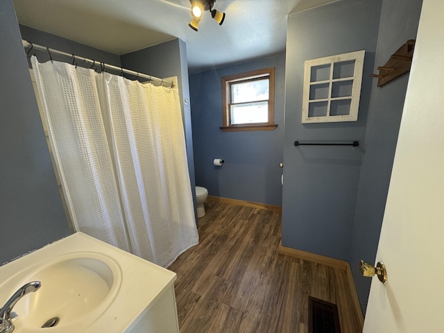 bathroom with sink, hardwood / wood-style floors, a shower with curtain, and toilet