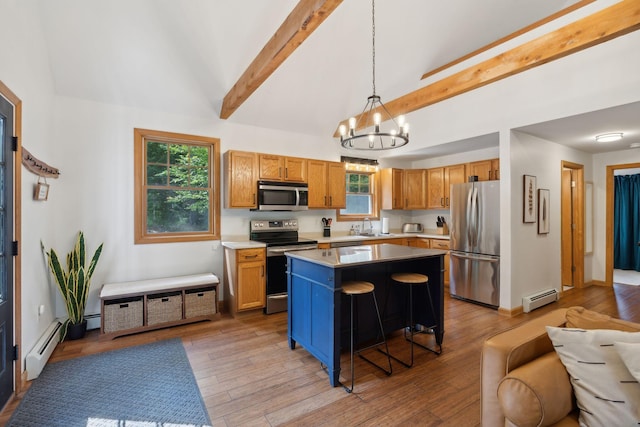 kitchen featuring appliances with stainless steel finishes, a kitchen breakfast bar, a baseboard radiator, a center island, and decorative light fixtures