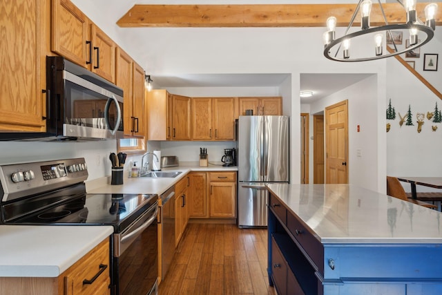 kitchen with hardwood / wood-style flooring, sink, a notable chandelier, a kitchen island, and stainless steel appliances