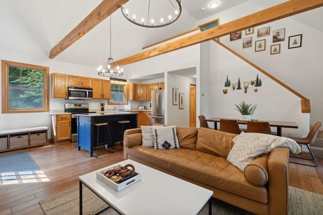 living room featuring light hardwood / wood-style flooring, beam ceiling, a chandelier, and a healthy amount of sunlight