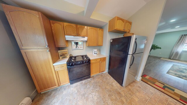 kitchen featuring black / electric stove, stainless steel refrigerator, light wood-type flooring, light brown cabinetry, and a baseboard radiator