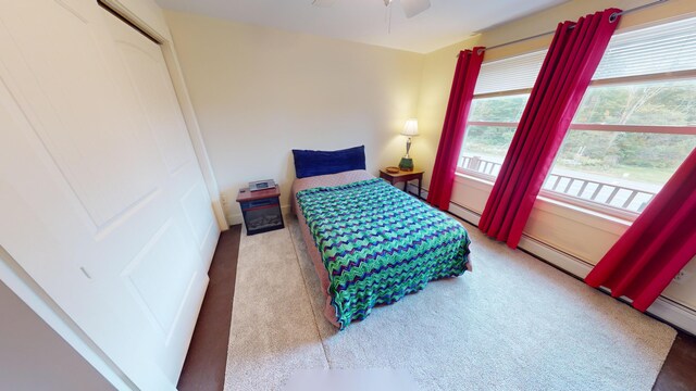 bedroom with a baseboard radiator, a closet, ceiling fan, and carpet flooring