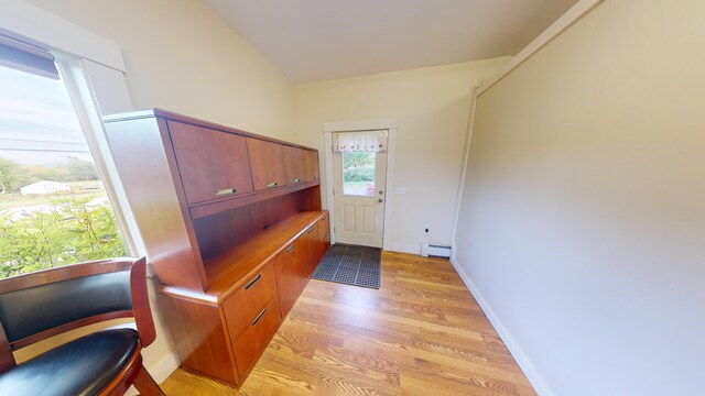 entryway with light hardwood / wood-style floors, lofted ceiling, and a baseboard heating unit