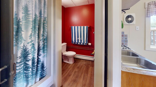 bathroom featuring a shower with shower curtain, baseboard heating, hardwood / wood-style floors, and toilet