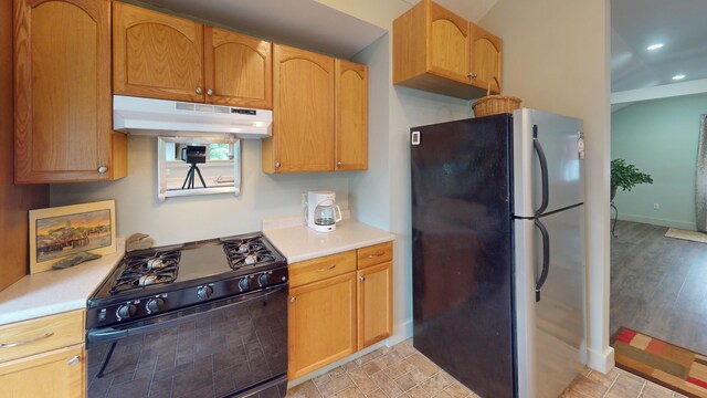 kitchen with light hardwood / wood-style flooring, black gas range oven, and stainless steel fridge