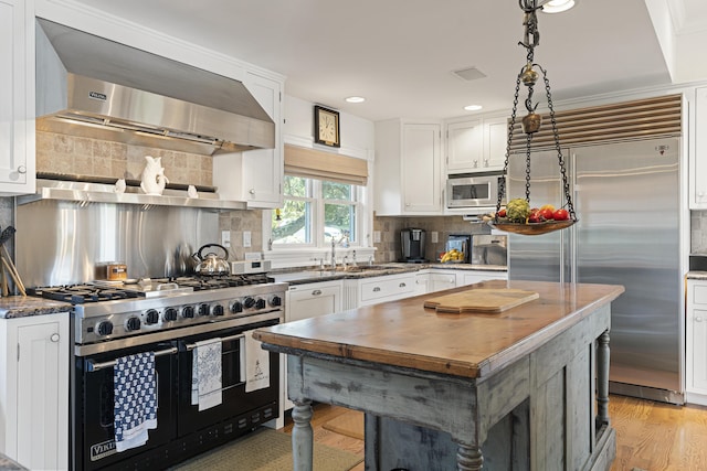 12 Steamboat Wharf Ln, Harpswell, ME 04079 - kitchen with built in appliances, wall chimney exhaust hood, white cabinets, tasteful backsplash, and a sink