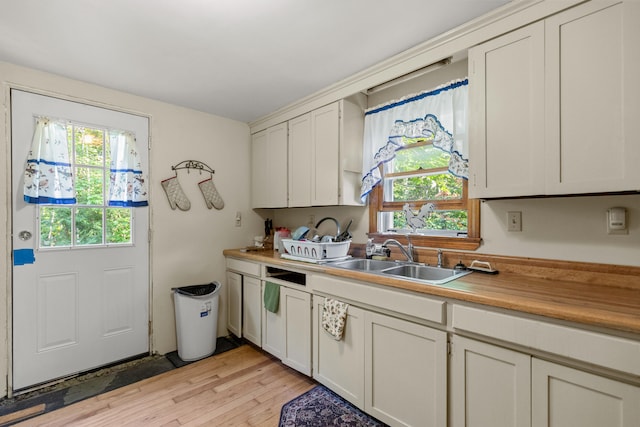 kitchen with light wood-type flooring, white cabinetry, and sink