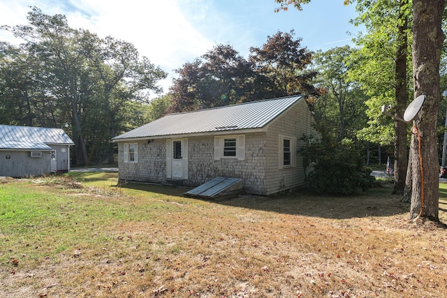 rear view of property with a lawn and metal roof