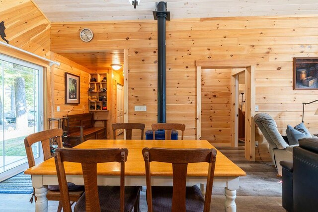 dining area featuring wooden walls, wood ceiling, and a wood stove