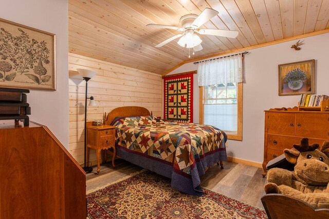 bedroom with wood-type flooring, vaulted ceiling, wood walls, ceiling fan, and wooden ceiling