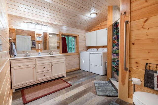 bathroom with vanity, lofted ceiling, wood walls, washing machine and dryer, and hardwood / wood-style floors