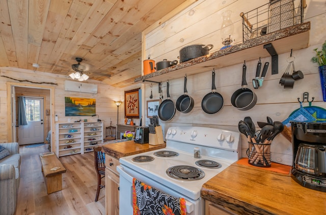 kitchen featuring butcher block counters, white electric stove, light wood-type flooring, ceiling fan, and wooden walls