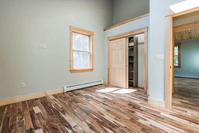 unfurnished bedroom with light wood-type flooring, a closet, and baseboard heating