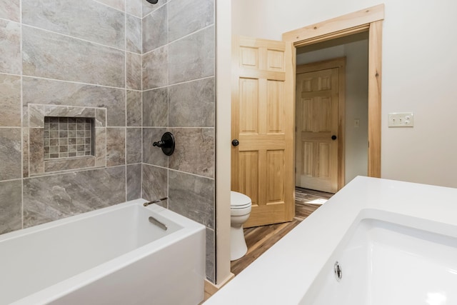 bathroom with tiled shower / bath, toilet, and hardwood / wood-style flooring