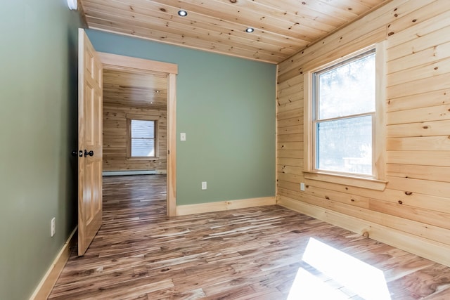 unfurnished room with wooden walls, hardwood / wood-style floors, and a healthy amount of sunlight