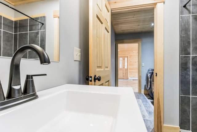 bathroom featuring wood ceiling, hardwood / wood-style flooring, sink, tiled shower, and washer and clothes dryer