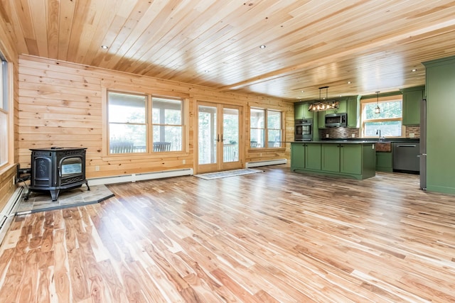 unfurnished living room featuring light hardwood / wood-style flooring, plenty of natural light, baseboard heating, and a wood stove