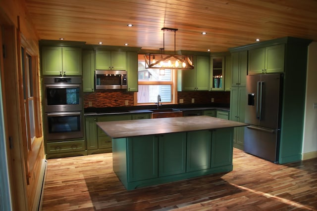 kitchen featuring appliances with stainless steel finishes, hanging light fixtures, green cabinetry, and hardwood / wood-style floors