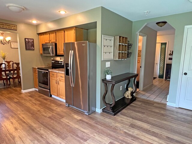 kitchen featuring a notable chandelier, stainless steel appliances, and light wood-type flooring