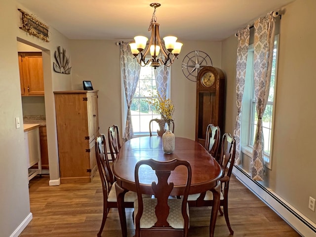 dining area featuring hardwood / wood-style flooring, baseboard heating, and a notable chandelier