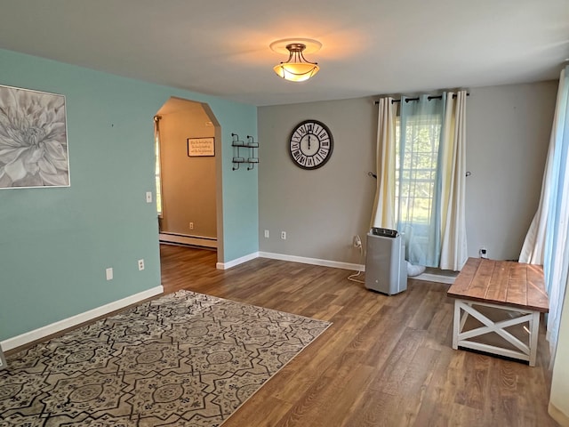 sitting room with a baseboard heating unit and wood-type flooring