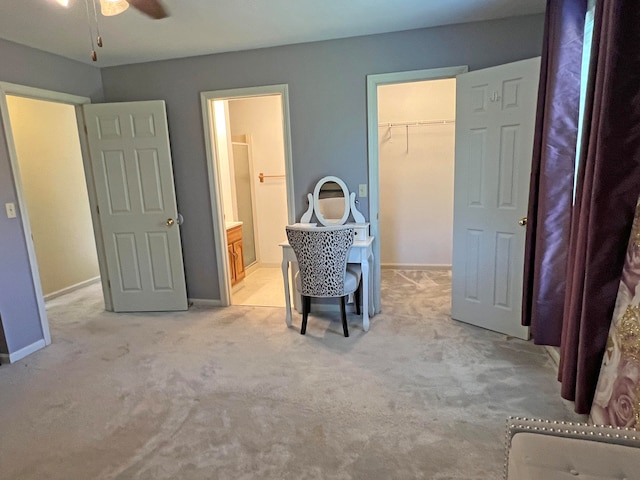 bedroom with light colored carpet, ceiling fan, a walk in closet, and a closet