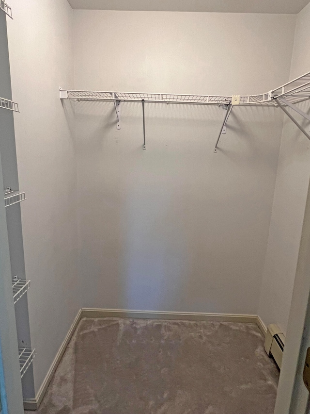 spacious closet featuring a baseboard heating unit and carpet