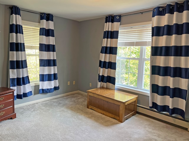 interior space with light carpet, a baseboard heating unit, and plenty of natural light