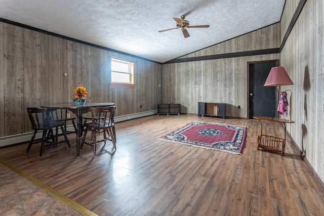 dining area with wood-type flooring, lofted ceiling, wood walls, and ceiling fan