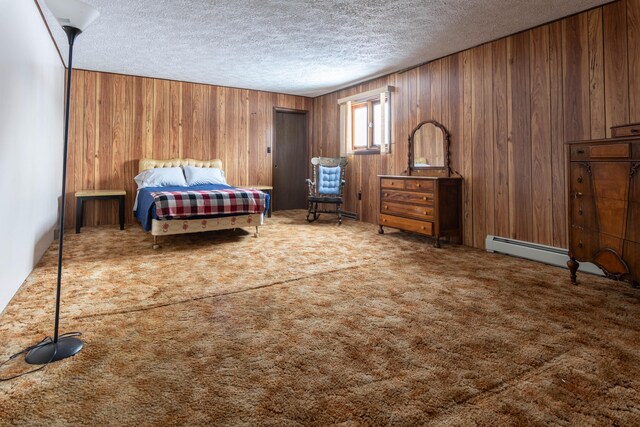 carpeted bedroom featuring a baseboard heating unit, a textured ceiling, and wooden walls