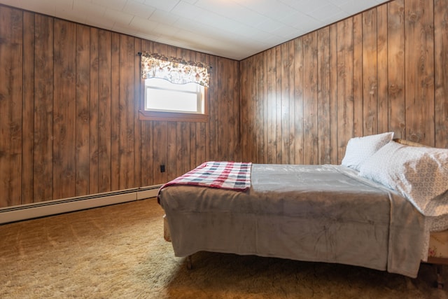 bedroom with a baseboard heating unit, wood walls, and carpet flooring