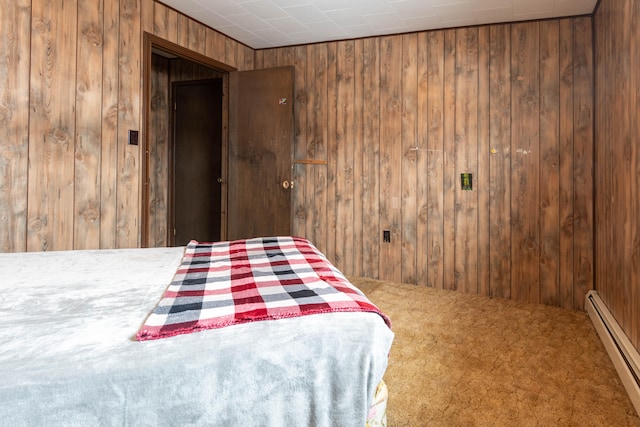 unfurnished bedroom with carpet floors, a baseboard radiator, and wood walls