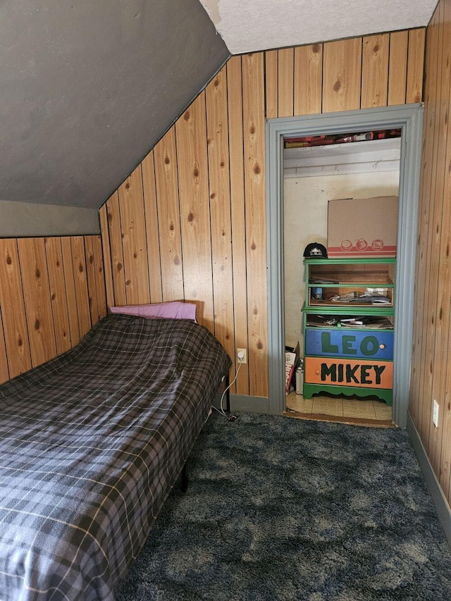 carpeted bedroom featuring a textured ceiling, wooden walls, and vaulted ceiling