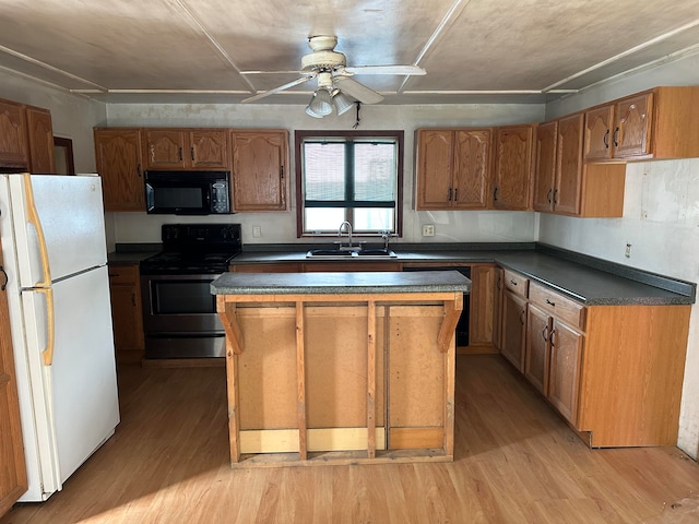 kitchen with light hardwood / wood-style floors, sink, a kitchen island, black appliances, and ceiling fan