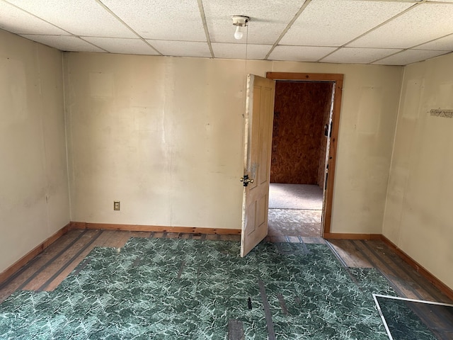 spare room featuring a drop ceiling and dark hardwood / wood-style flooring