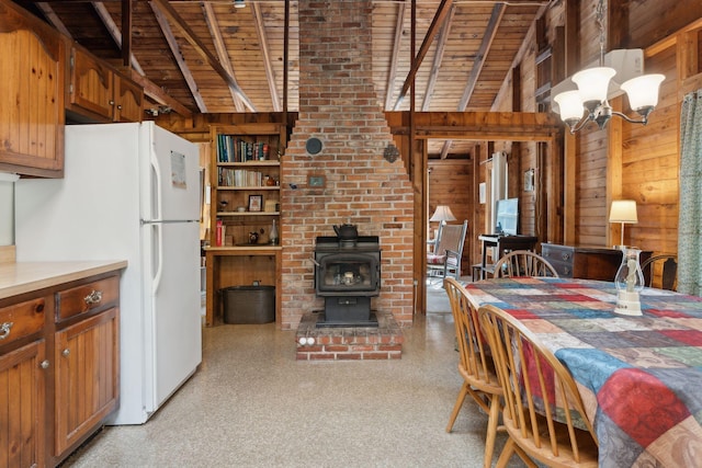 dining space with wood ceiling, lofted ceiling with beams, wood walls, a wood stove, and an inviting chandelier