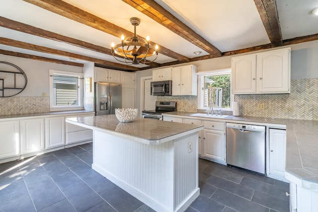 kitchen with stainless steel appliances, a center island, white cabinetry, and decorative light fixtures