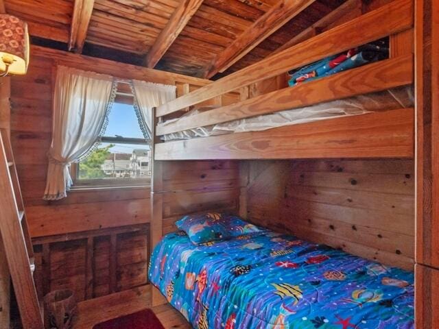 bedroom featuring beam ceiling, wood ceiling, and wood walls