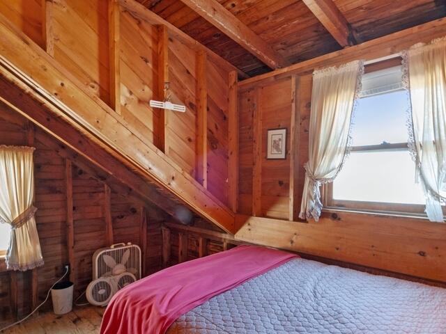 bedroom with wooden walls, lofted ceiling, and wooden ceiling