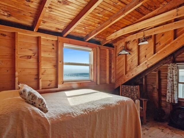 bedroom featuring wooden ceiling, wood walls, and lofted ceiling with beams