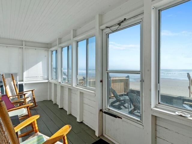 sunroom featuring a water view and a beach view