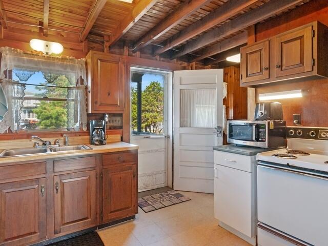 kitchen with beam ceiling, wood ceiling, white electric range, and sink