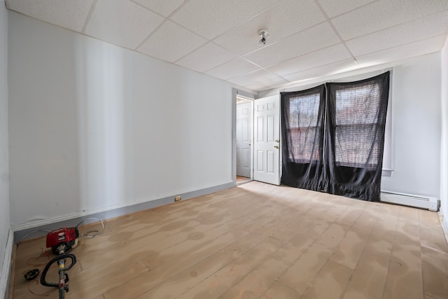 empty room featuring a baseboard radiator, a drop ceiling, and hardwood / wood-style flooring