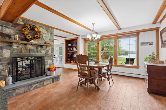 dining area featuring hardwood / wood-style floors, baseboard heating, a healthy amount of sunlight, and a stone fireplace