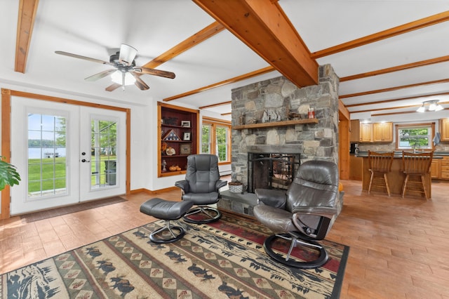 living room with beam ceiling, plenty of natural light, and a stone fireplace