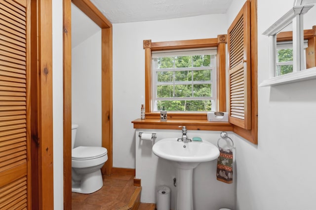 bathroom with a textured ceiling, toilet, and a wealth of natural light