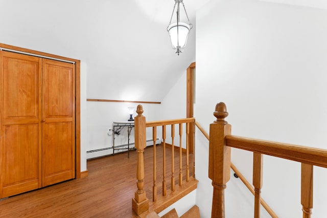 staircase featuring lofted ceiling, a baseboard radiator, and hardwood / wood-style flooring